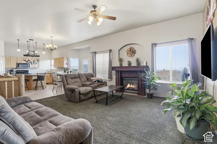 Living area featuring a fireplace with a wood mantel and arched architectural alcove, complemented by a ceiling fan with integrated lighting and multi-pendant kitchen island illumination