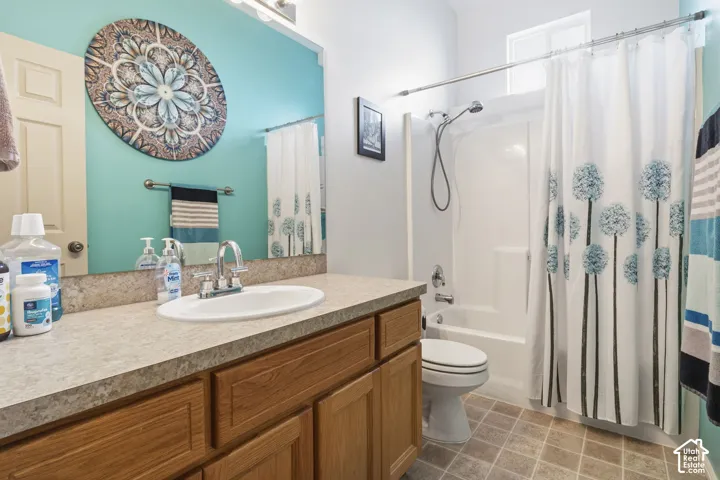 Bathroom featuring a wood-finish vanity cabinet, stone-patterned countertop with an integrated oval sink, full-width mirror, and a tub-shower combination with a white surround