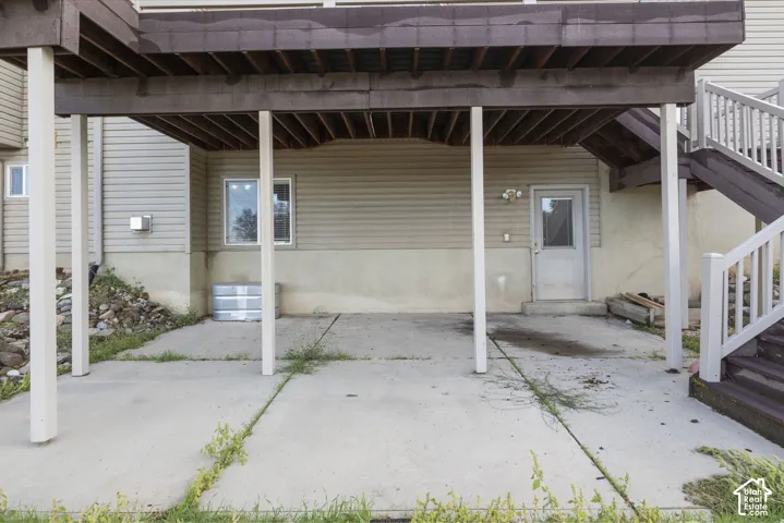 Covered carport with concrete flooring and sturdy support columns, providing sheltered parking and storage space