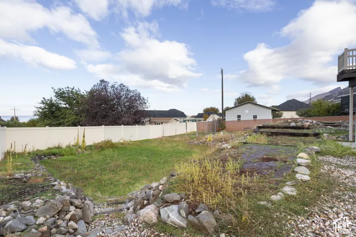 Backyard featuring a privacy fence, terraced landscape design, boulder retaining walls, and mountain scenery
