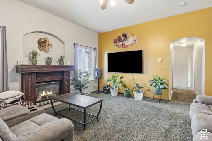 Living area featuring a fireplace with a wood mantel, an arched wall niche, carpeted flooring, and an arched doorway