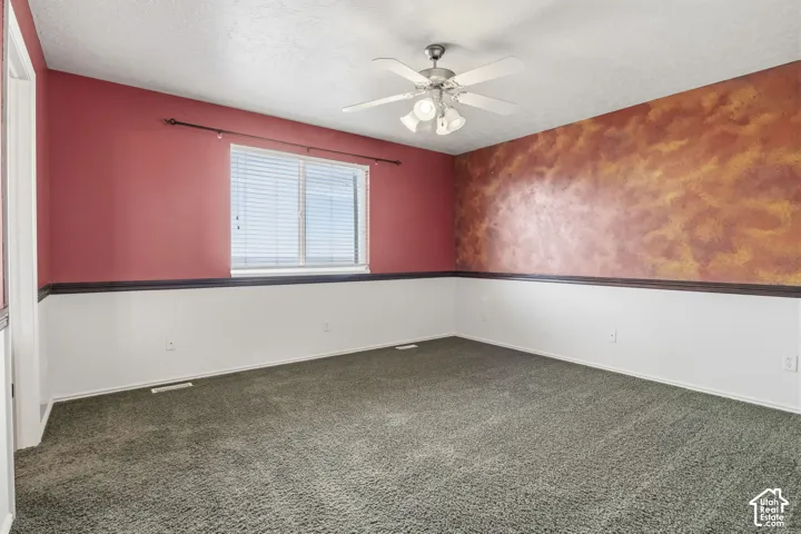 Room featuring wall-to-wall carpeting, chair rail molding, and a central ceiling fan with integrated lighting