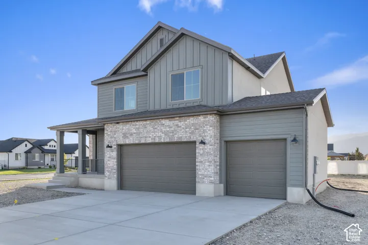 Two-story residence featuring vertical and horizontal siding, a stone veneer facade, a covered front porch, and a three-car garage
