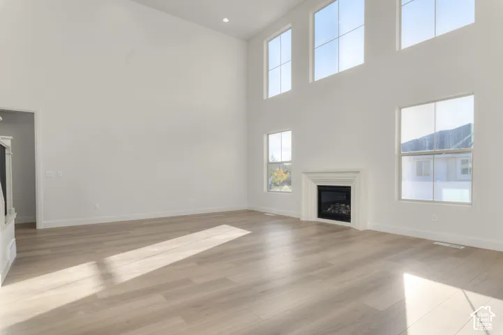Expansive interior space with double-height ceilings, wood-finish flooring, multi-pane windows, and a built-in fireplace with a tiered surround