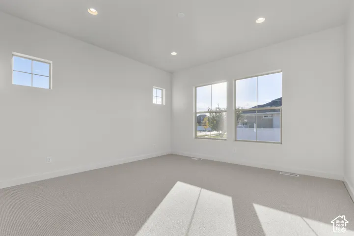 Neutral interior space featuring high ceilings, recessed lighting, expansive multi-pane windows, and wall-to-wall carpeting