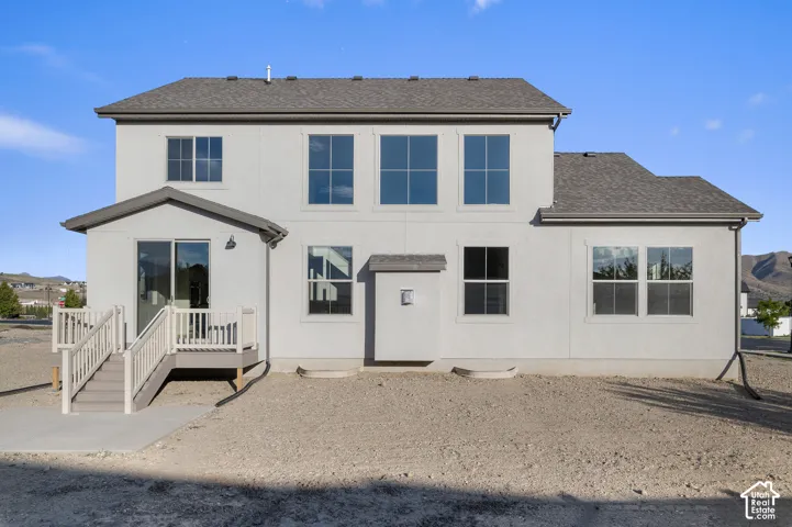 Two-story stucco exterior featuring a composite deck with railing, sliding glass door, and large multi-pane windows