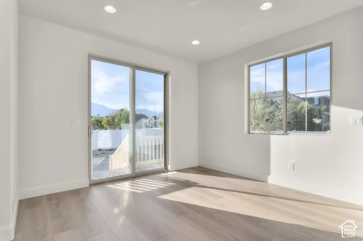 Bright room featuring wood-finish flooring, recessed lighting, grid-pane windows, and sliding glass doors with access to a deck