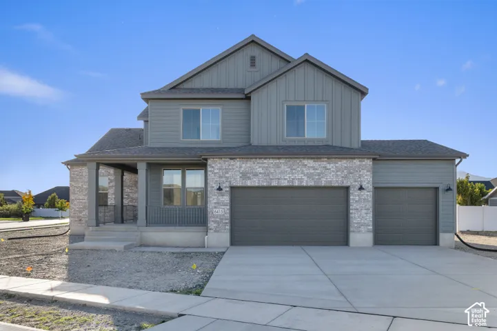 Multi-story residence featuring a combination of vertical siding and stone veneer, a covered porch with metal railing, and a three-car garage
