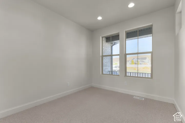 Neutral-toned interior room featuring wall-to-wall carpeting, dual-pane windows, and recessed lighting