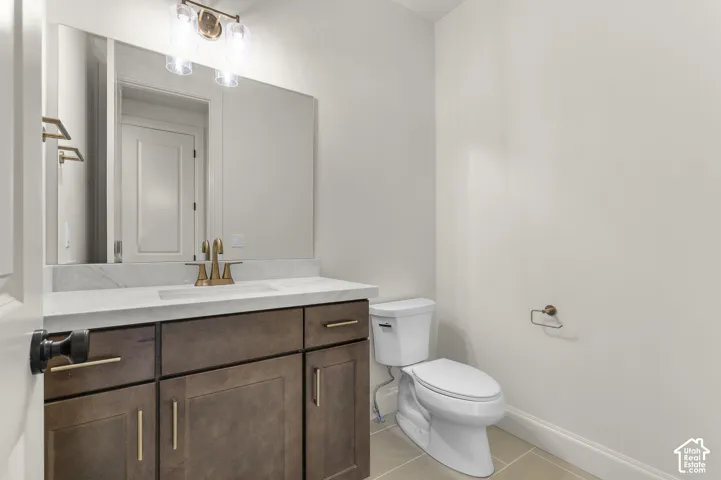 Restroom featuring dark wood-finish cabinetry, a stone-surface countertop with an integrated rectangular sink, metallic faucet hardware, and a large wall-mounted mirror with integrated light fixtures
