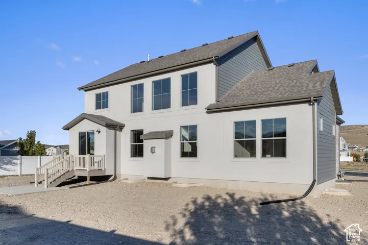 Multi-level exterior featuring stucco and horizontal siding, asphalt shingle roofing, elevated wood deck with railing, and grid-pane windows
