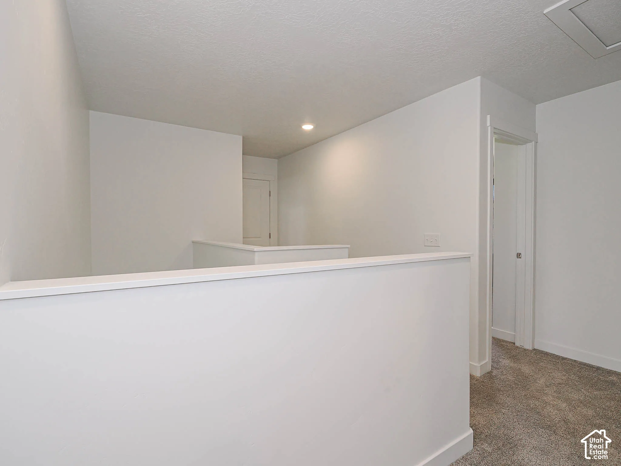 Open area featuring neutral wall paint, recessed lighting, carpeted flooring, and a half-wall partition