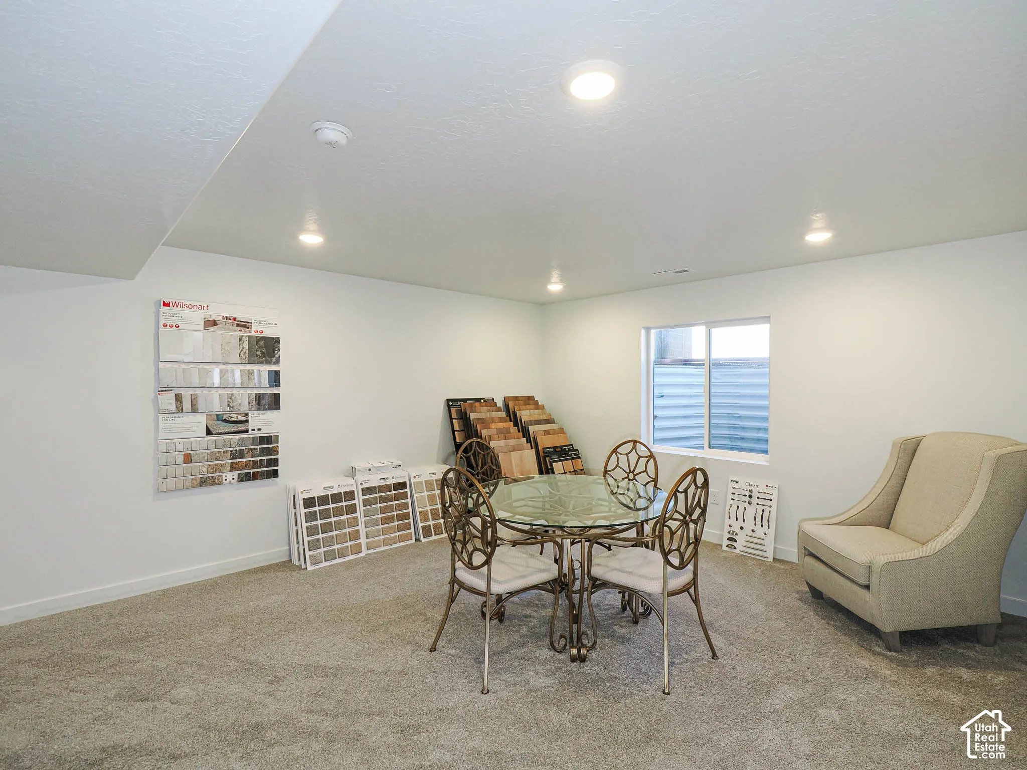 Interior space featuring neutral wall tones, wall-to-wall carpeting, recessed ceiling lighting, and a window with a window well