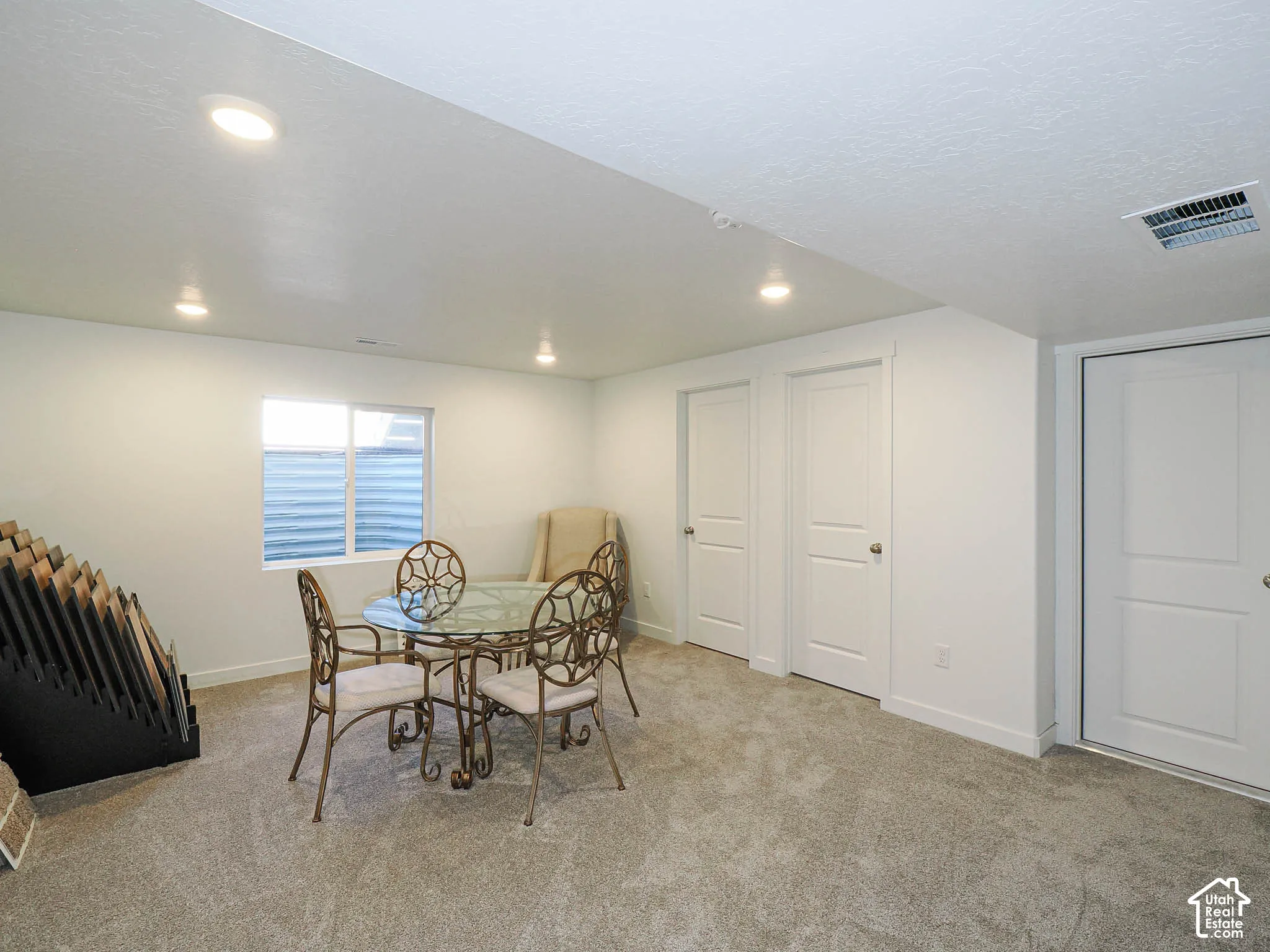 Interior space featuring neutral-toned carpeting, recessed ceiling lighting, a window with an egress well, and two interior doors with panel detailing