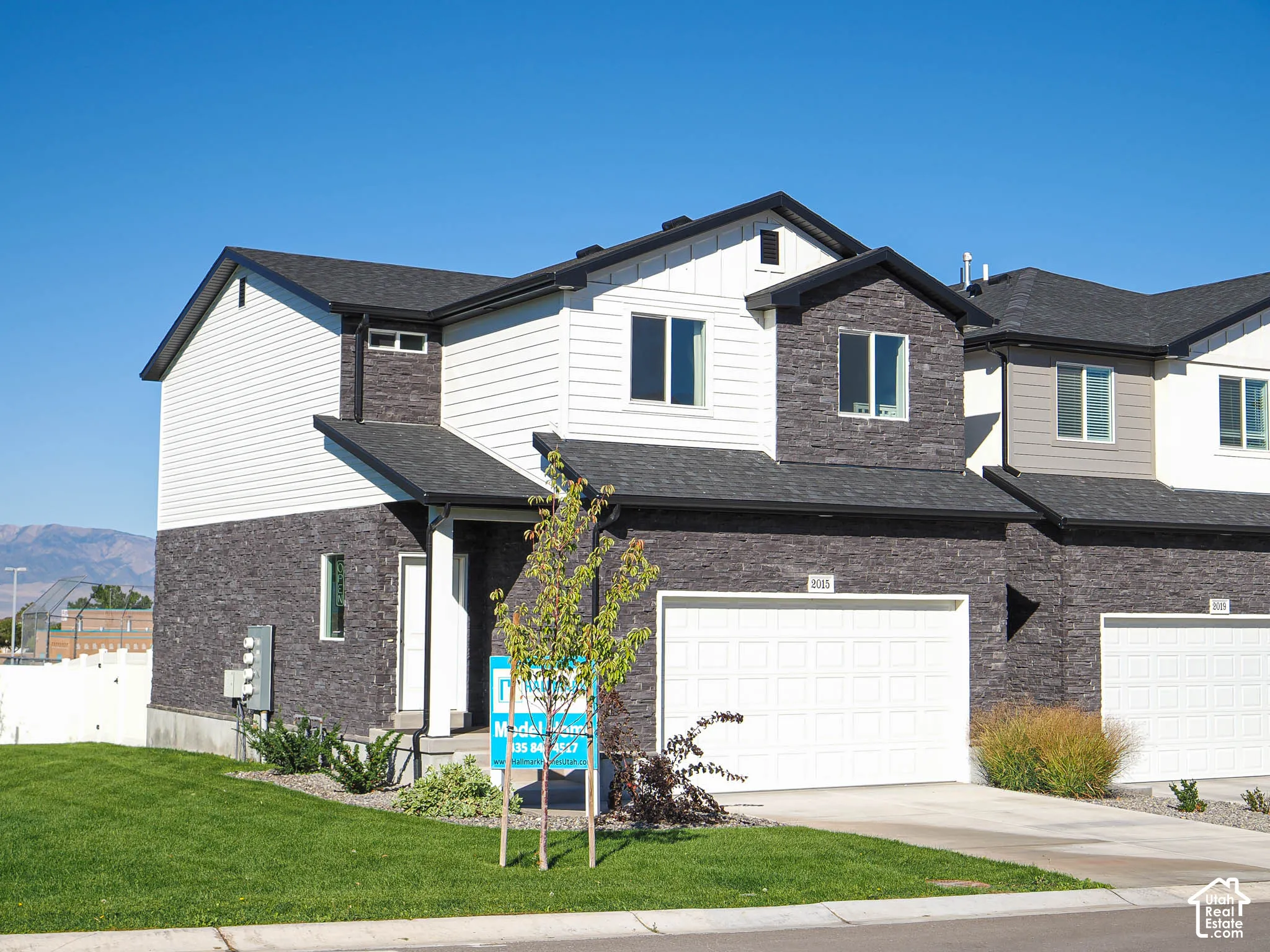 Exterior featuring a mixed-material facade of stone veneer and horizontal siding, a pitched shingle roof, and a built-in garage