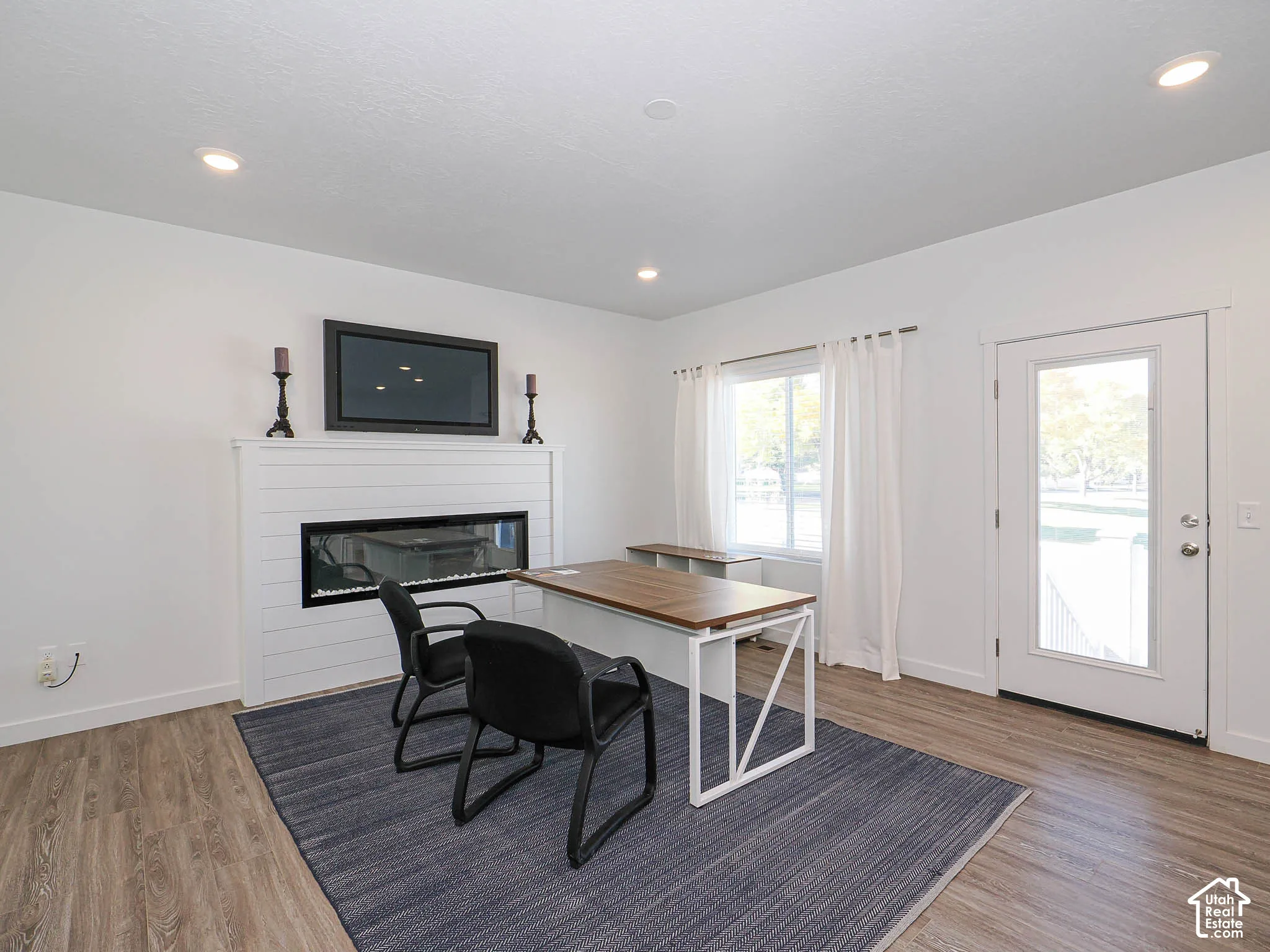 Horizontal shiplap fireplace surround featuring a linear electric insert, recessed ceiling lighting, and wood-finish flooring