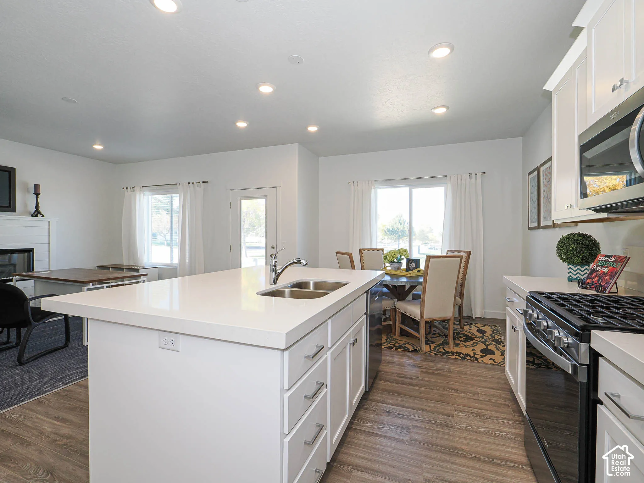 Kitchen featuring an island with a dual-basin sink, white cabinetry, quartz countertops, recessed lighting, and wood-finish flooring