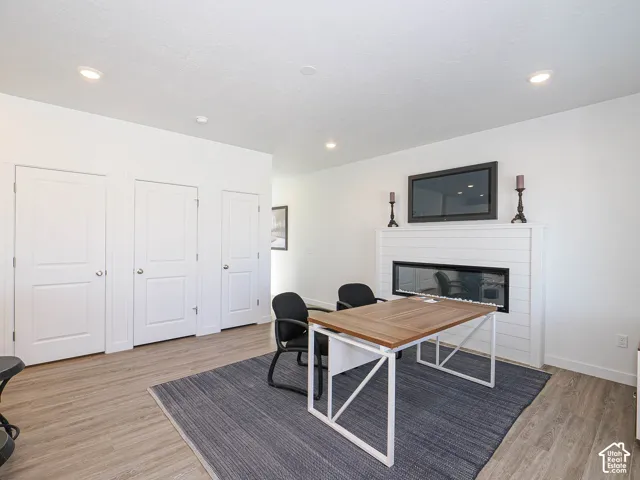 Room interior featuring wood-finish flooring, recessed lighting, white panel doors, and a linear fireplace with white shiplap-style surround