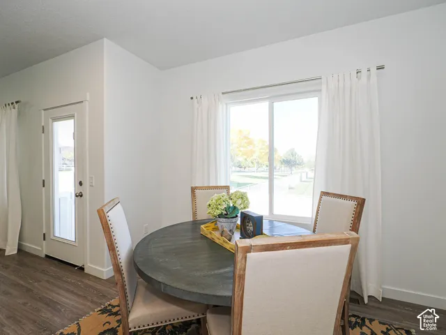 Neutral-toned room featuring wood-finish flooring, a glass-paneled entry door, and a sliding window with metallic curtain hardware