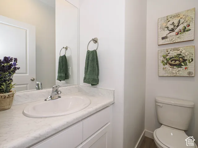 White vanity featuring a stone-composite countertop, integrated oval basin, brushed chrome faucet, and large wall-mounted mirror