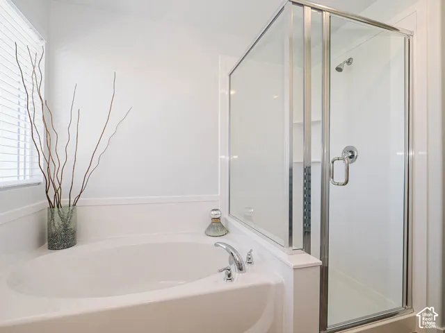 Oval soaking tub with chrome fixtures, accompanied by a separate glass-enclosed shower stall