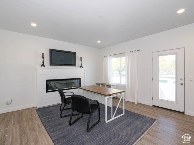 Horizontal shiplap fireplace surround featuring a linear electric insert, recessed ceiling lighting, and wood-finish flooring