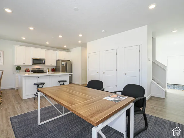 Kitchen featuring white cabinetry, an island with countertop seating, stainless steel appliances, recessed lighting, and wood-finish flooring