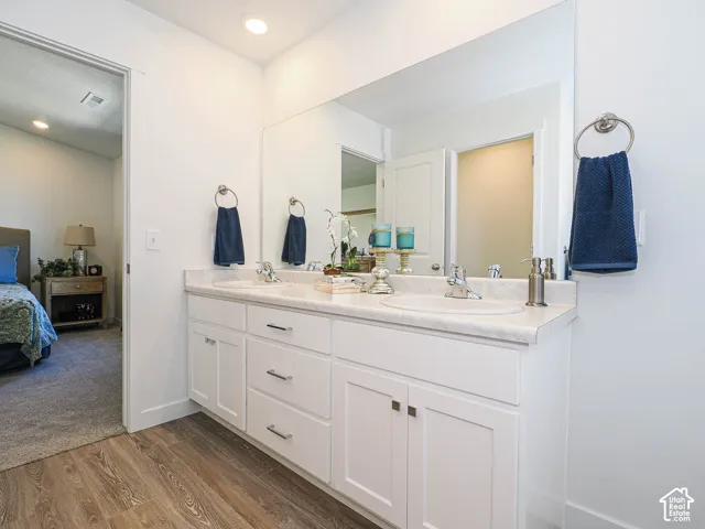 Double vanity featuring white shaker-style cabinetry, chrome hardware, integrated sinks, and a full-width wall mirror