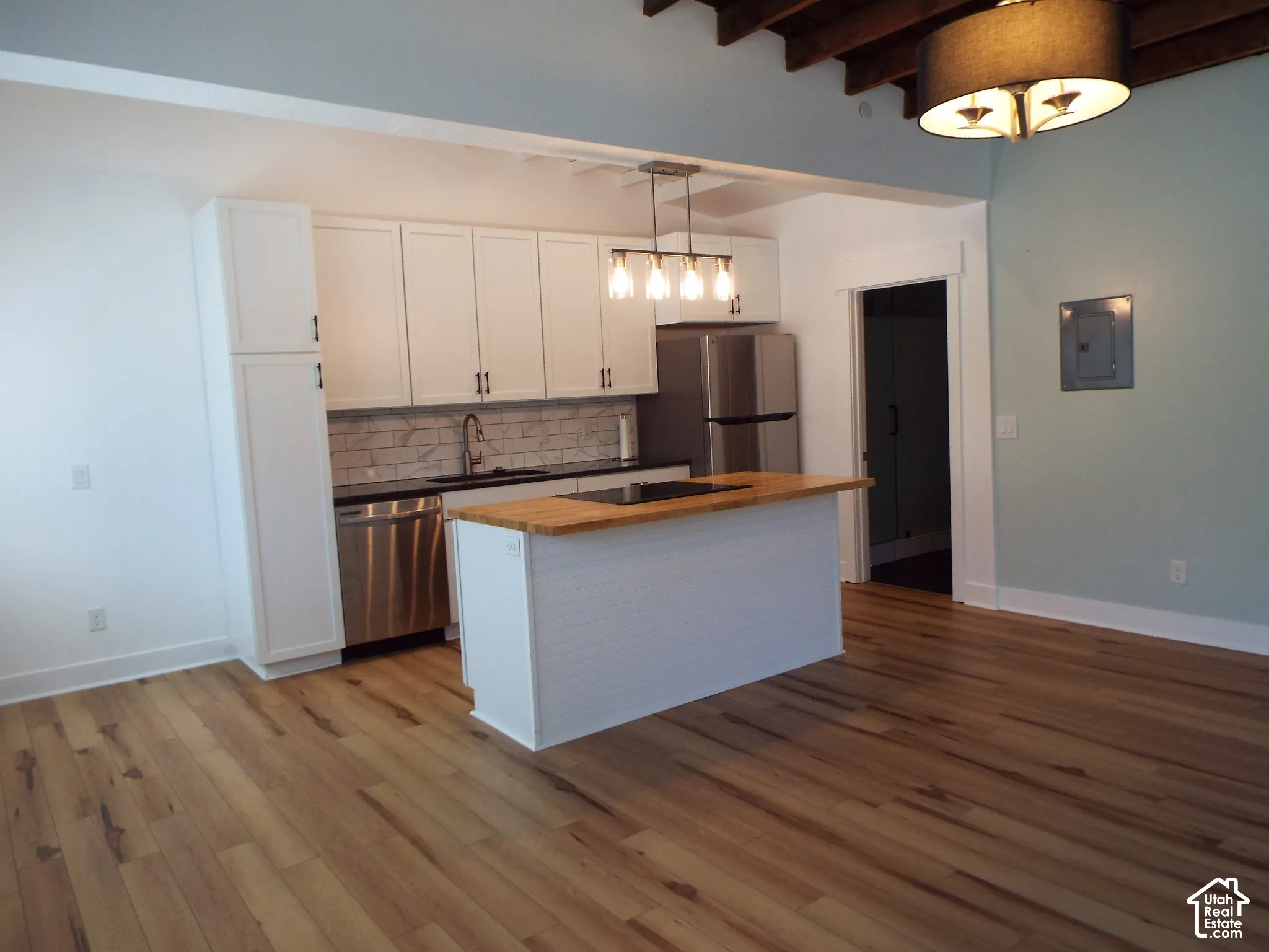 Kitchen featuring shaker-style cabinetry, wood-finish flooring, a butcher-block island countertop, subway tile backsplash, and exposed ceiling beams
