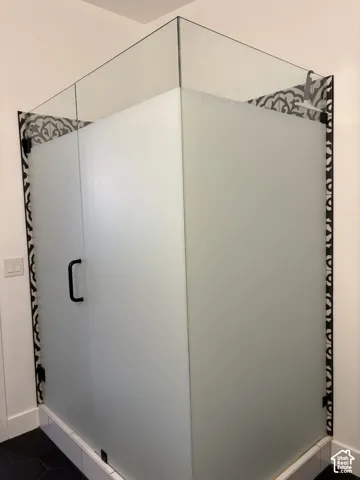Walk-in shower featuring frosted glass panels, black hardware, and patterned tile accents