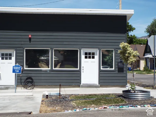 Dark-toned horizontal lap siding, flat roofline, white multi-pane exterior doors, and large windows with white trim