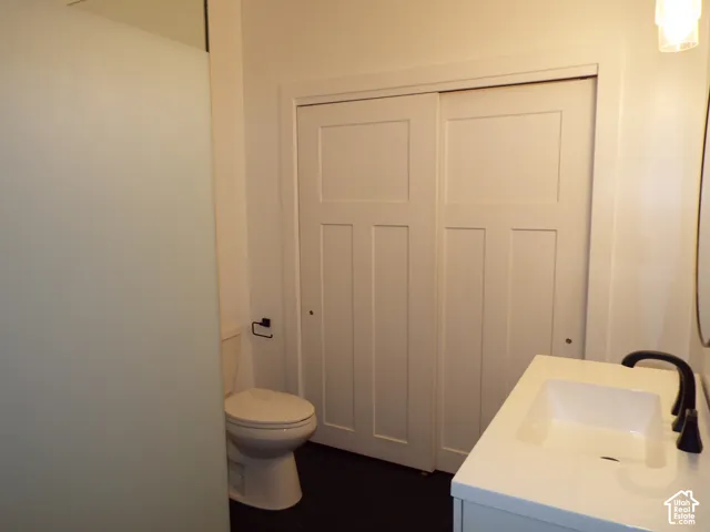 Bathroom featuring a vanity with an integrated rectangular sink and matte black faucet, frosted glass shower enclosure, two-panel sliding closet doors, and dark hexagonal floor tile