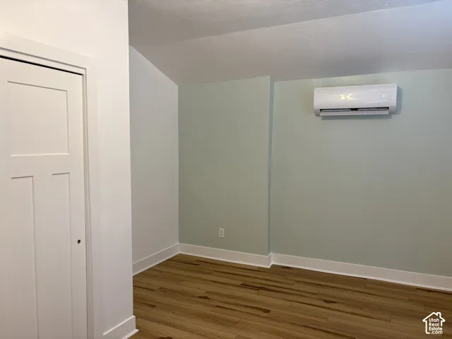 Interior space featuring wood-finish flooring, a wall-mounted ductless mini-split HVAC unit, and a Shaker-style door