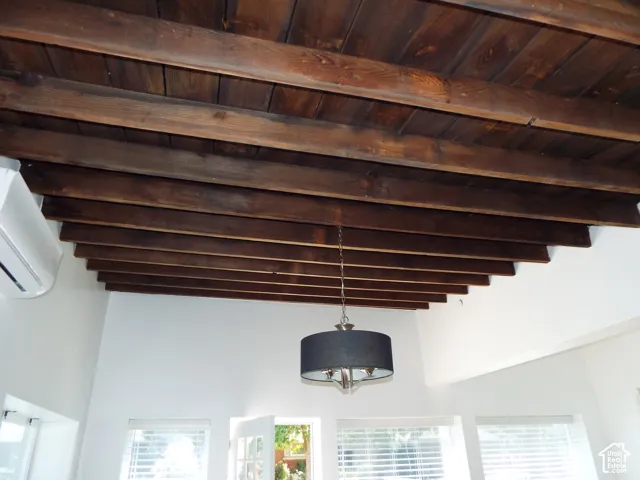 Exposed wood-beam ceiling featuring dark-finish timbers and a suspended drum-style light fixture