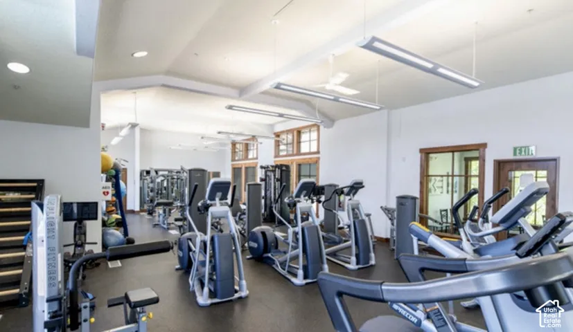 Fitness center featuring vaulted ceilings, linear LED lighting, and resilient rubberized flooring