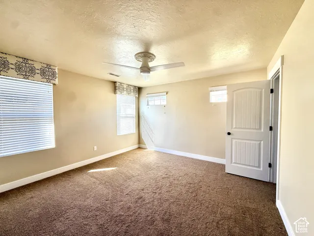 Neutral-toned 3rd bedroom features plush wall-to-wall carpeting, multiple windows, with upgraded fabric valances and a ceiling-mounted fan with integrated light and huge oversized closet