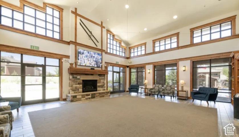 Clubhouse meeting spaces features high ceilings, multi-pane windows, wood-trimmed architectural accents, and a floor-to-ceiling stone fireplace