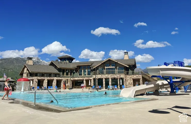 Swimming pool area featuring a water slide, mushroom water feature, and mountain backdrop