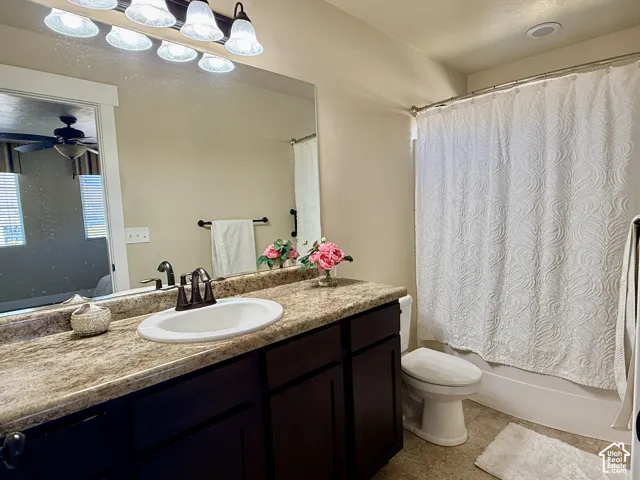 Bathroom featuring a dark-finish wood vanity, stone-patterned countertop with an integrated oval sink, matte-finish bronze hardware, and a large-format mirror with multi-bulb overhead lighting