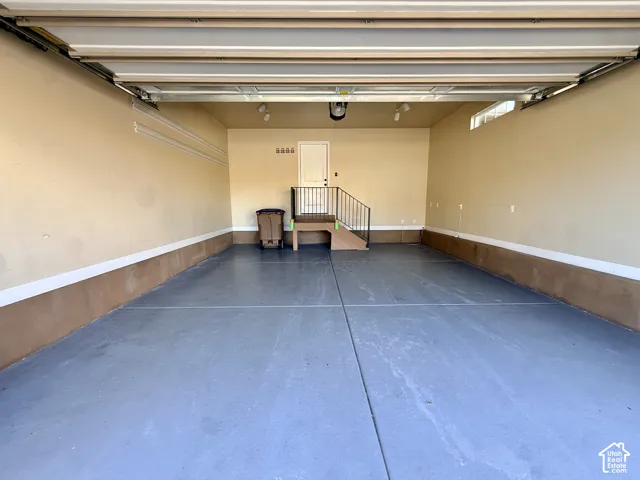 MASSIVE, finished multi-car garage featuring tons of storage space, gladiator storage racks, a smooth-finish floor, elevated access platform with metal railing, and overhead lighting