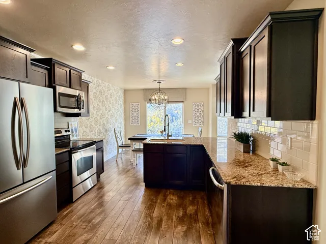 Brand new refrigerator in the kitchen! The dining area features dark wood cabinetry, granite stone countertops, stainless steel appliances, white subway tile backsplash, and wood-finish flooring