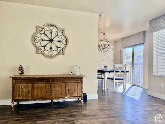 Gorgeous wood-finish flooring, stunning orb-style chandelier with ceiling medallion, sliding glass door, and beautiful wallpapered feature wall.