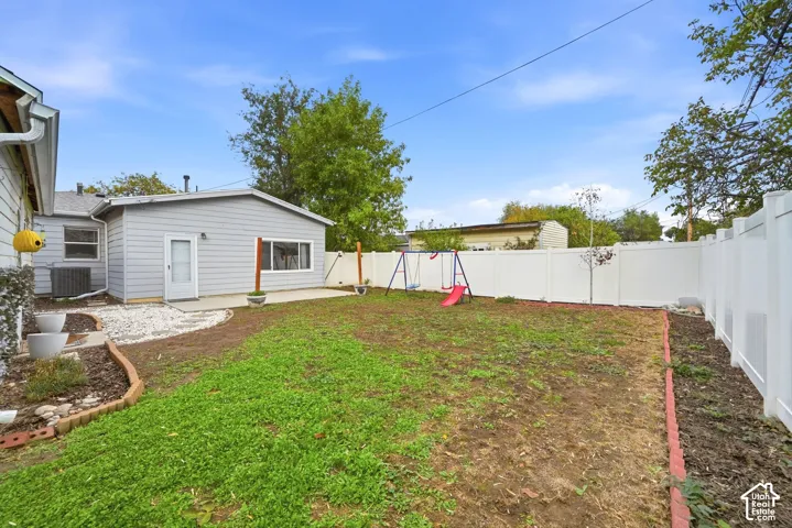 Another view of the backyard, looking toward the back of the house. A rock path leads from the patio, and the central air unit sits beside the house.