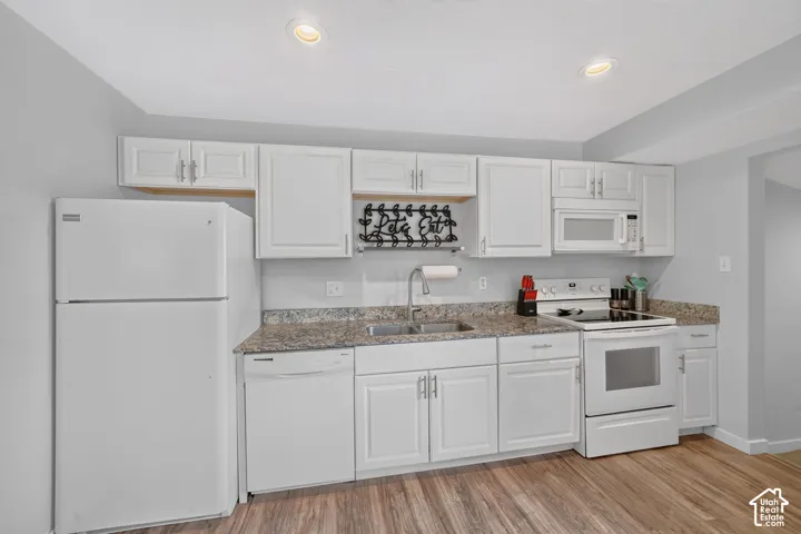 The kitchen has white cabinets and granite countertops, with the dishwasher, electric range and refrigerator along one wall. The range and refrigerator are included.