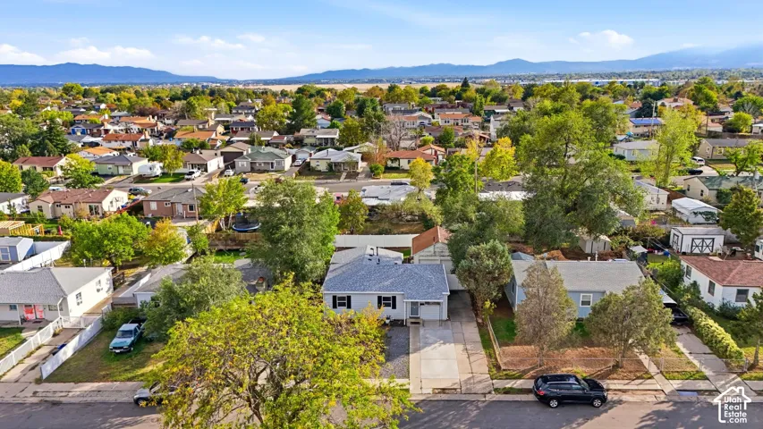 Kearns, in the heart of the Salt Lake Valley, with mountains on the horizon. The lot sits on a tree-lined street, with the detached garage and fenced backyard behind the house.