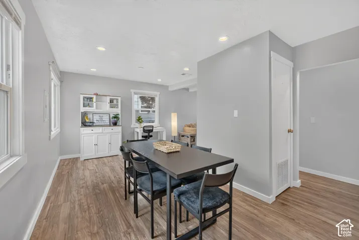 Another view of the dining area, with a table, a white hutch and a desk nook by the window. The hall opens beside it.