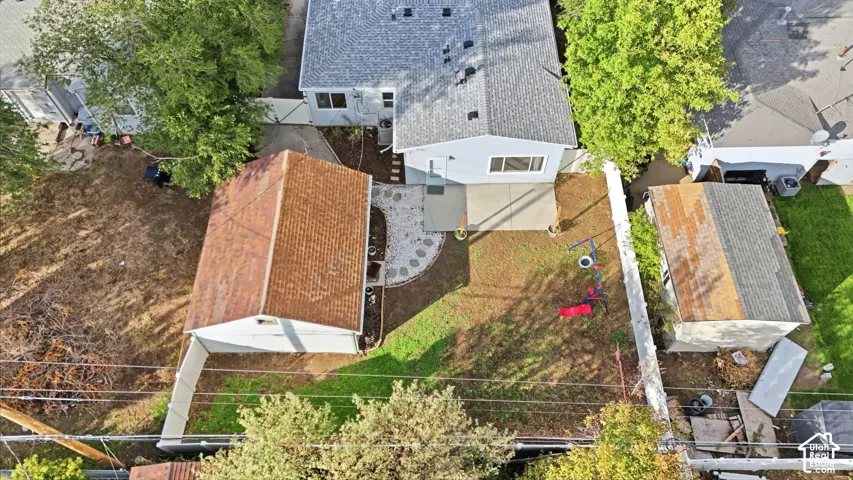 Looking down, the fenced backyard sits between the house and the detached garage, with the patio and rock path in between and the new roof on top.