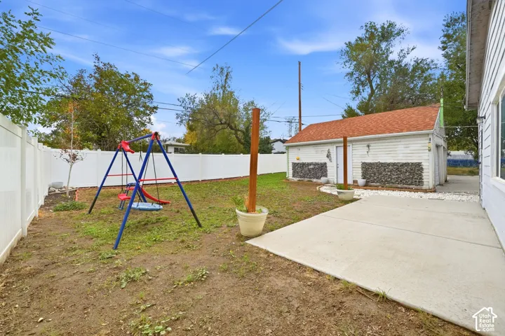 A concrete patio off the back of the house opens to a fully fenced lawn, with the detached garage along one side.