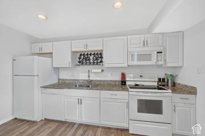 Another view of the kitchen, with the over-the-range microwave and a run of white upper cabinets above the granite counters.