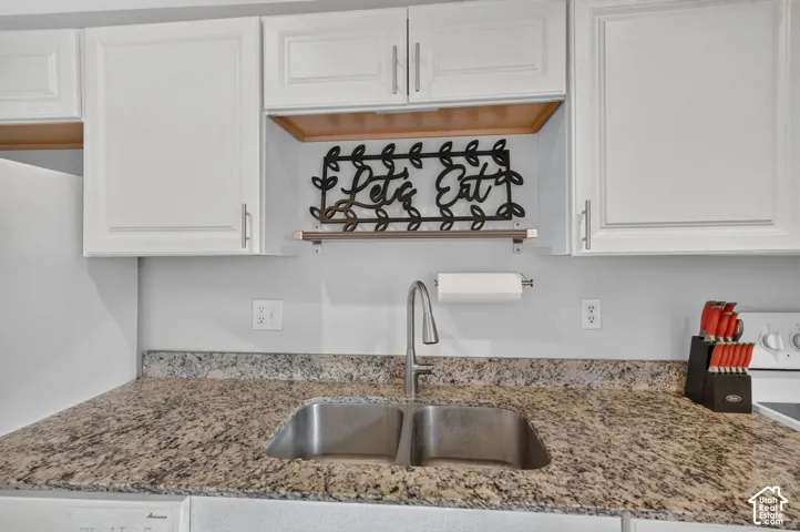 The granite counters wrap a double-bowl stainless sink with a pull-down faucet, with the dishwasher beside it.
